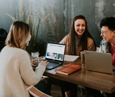 three people sitting in front of table laughing together