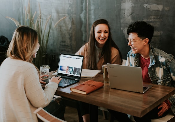 three people sitting in front of table laughing together