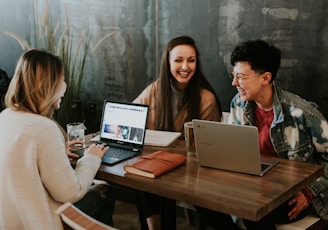 three people sitting in front of table laughing together