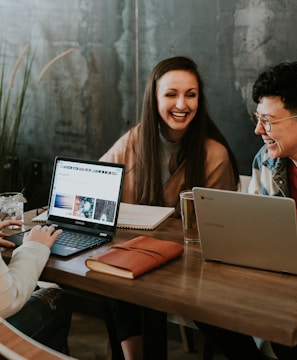 three people sitting in front of table laughing together