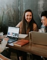 three people sitting in front of table laughing together