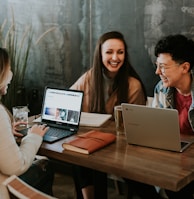 three people sitting in front of table laughing together