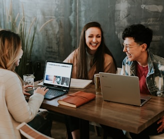 three people sitting in front of table laughing together