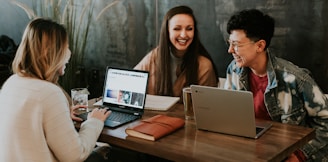 three people sitting in front of table laughing together