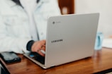 shallow focus photography of person using gray Samsung laptop