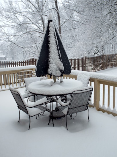 Weatherproof metal patio table cover protecting a table during a gentle rain.
