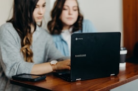 two woman using laptop