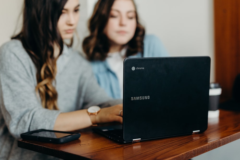 duas mulheres usando laptop