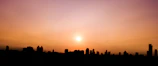 Digital illustration of a cityscape at sunset with warm hues.