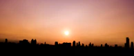 A scenic view of a famous global city skyline bathed in the purple and orange glow of sunset.