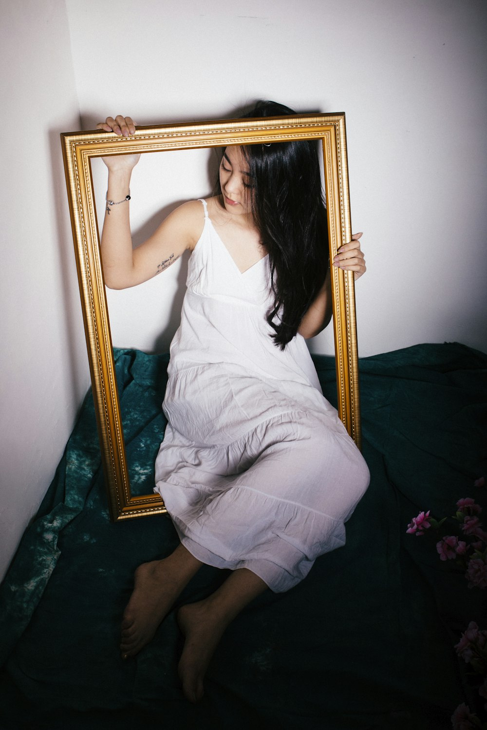 woman sitting on rectangular brown wooden frame near white painted wall