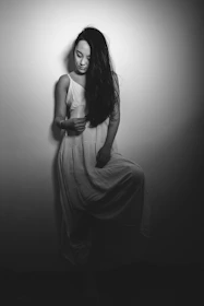 Softly lit portrait of a woman wearing a flowing white dress with subtle black accents.