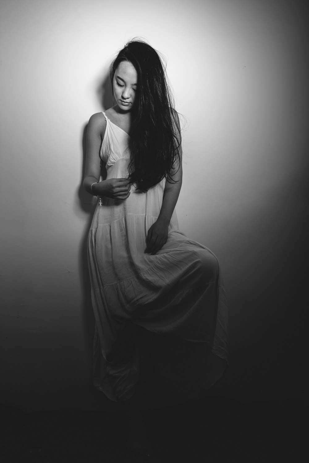 woman wearing spaghetti strap maxi dress leaning on wall