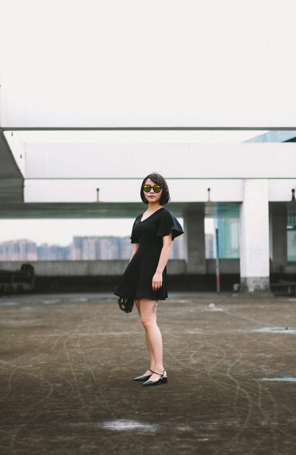 woman in black minidress and black sunglasses standing on street