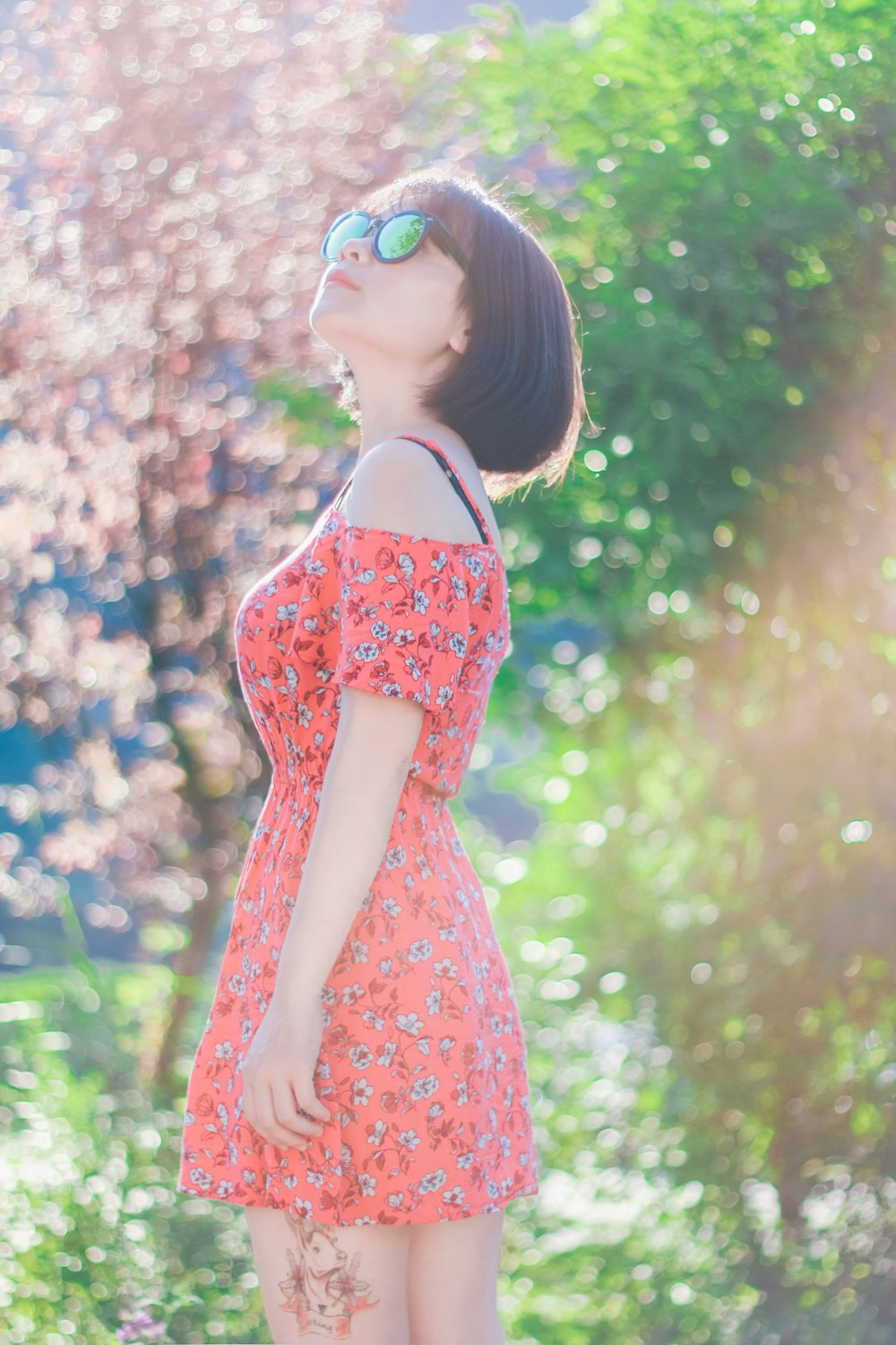 woman wearing dress and sunglasses standing near trees