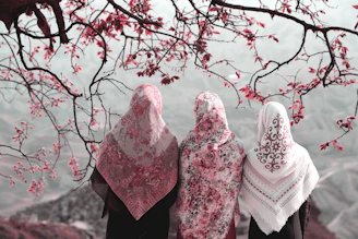 three Muslim women standing side by side near tree