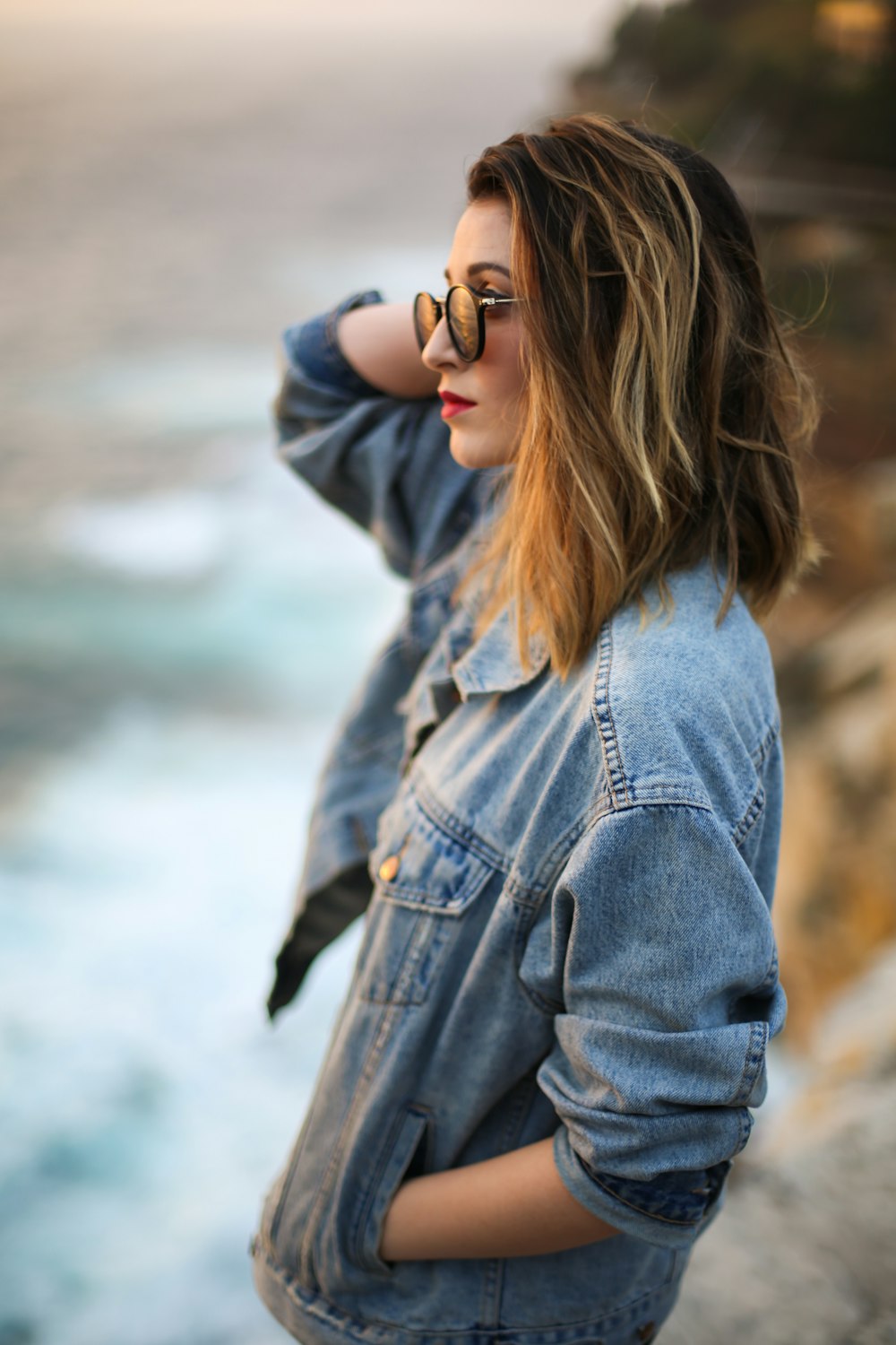 femme en veste en jean bleue debout à côté de la falaise