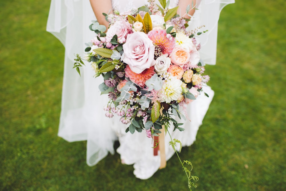 緑の芝生の上に立つ花束を持った新婚の女性