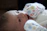 A joyful newborn wrapped snugly in a soft, pastel-colored blanket under gentle sunlight.