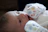 A joyful newborn wrapped snugly in a soft, pastel-colored blanket under gentle sunlight.