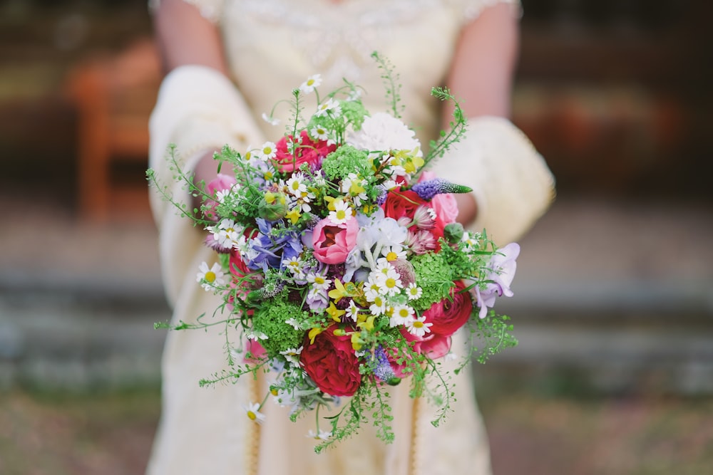 pink and white petaled flower arrangement on person's hand