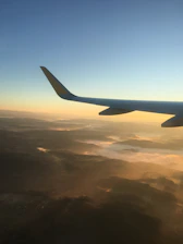 A sleek airplane soaring above the clouds with a sunrise backdrop symbolizing new beginnings.