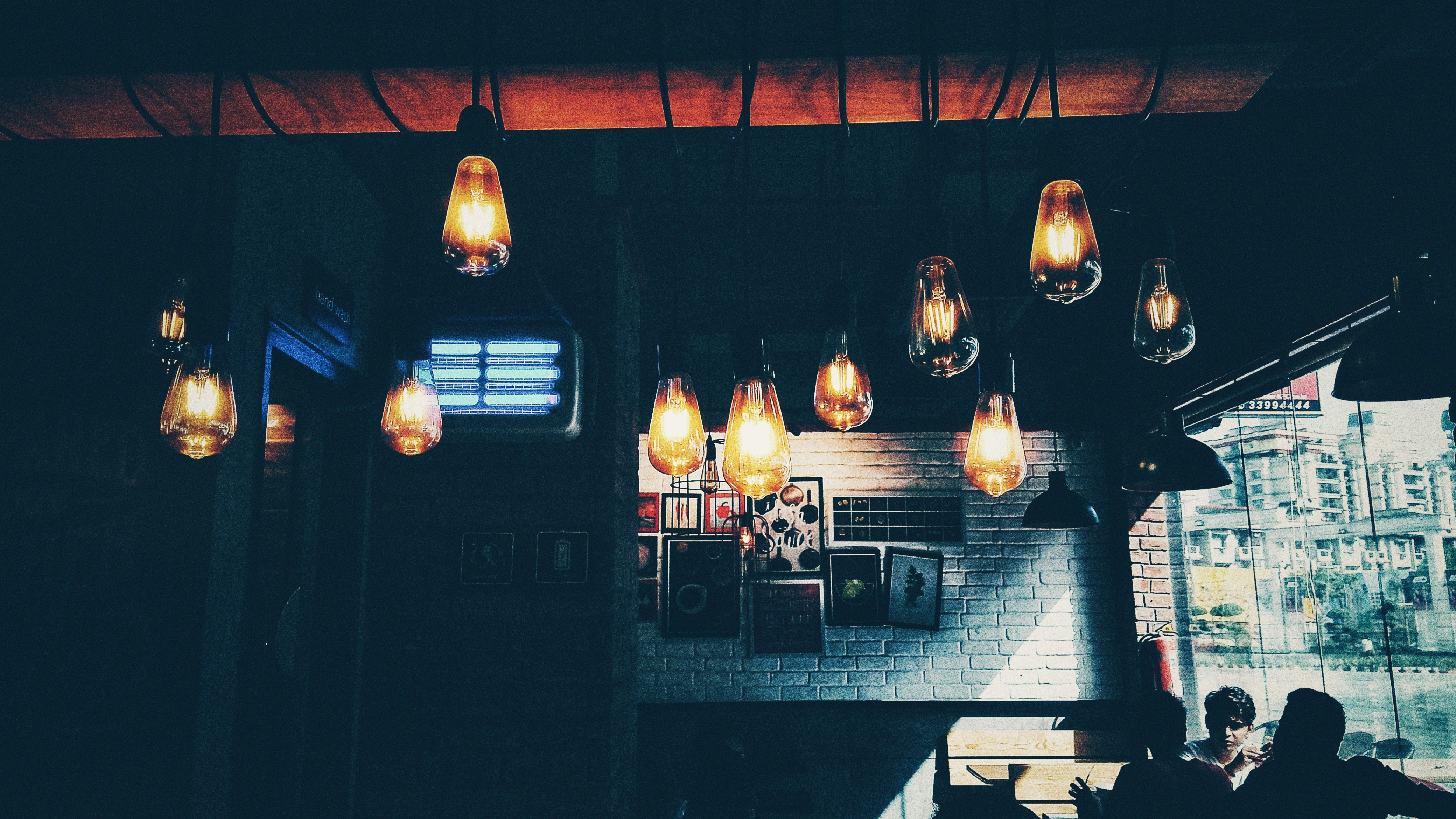 Warm cafe interior with exposed brick walls, hanging Edison bulbs, and cozy seating arrangements