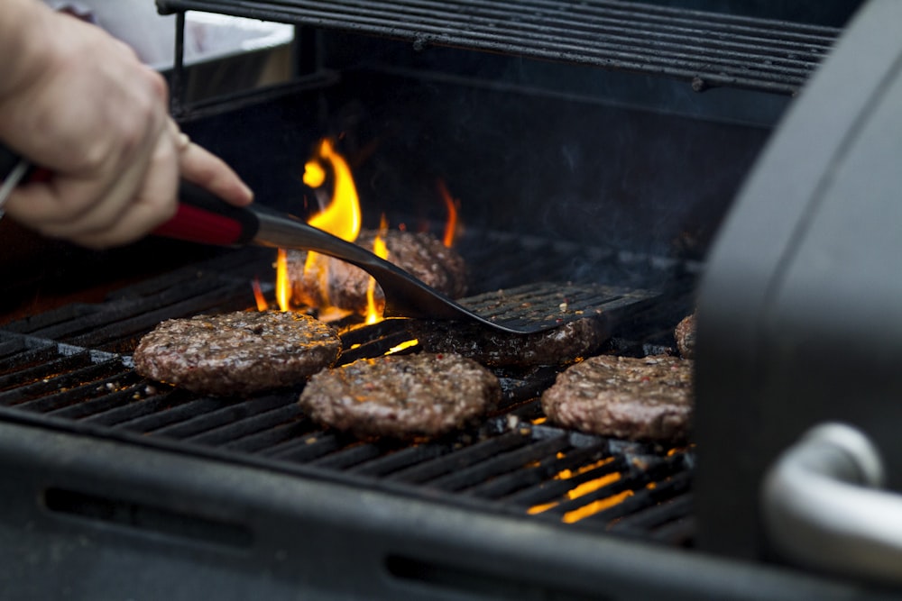 person grilling hamburger patties