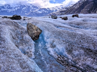 ice glacier with boulder on top near mountains