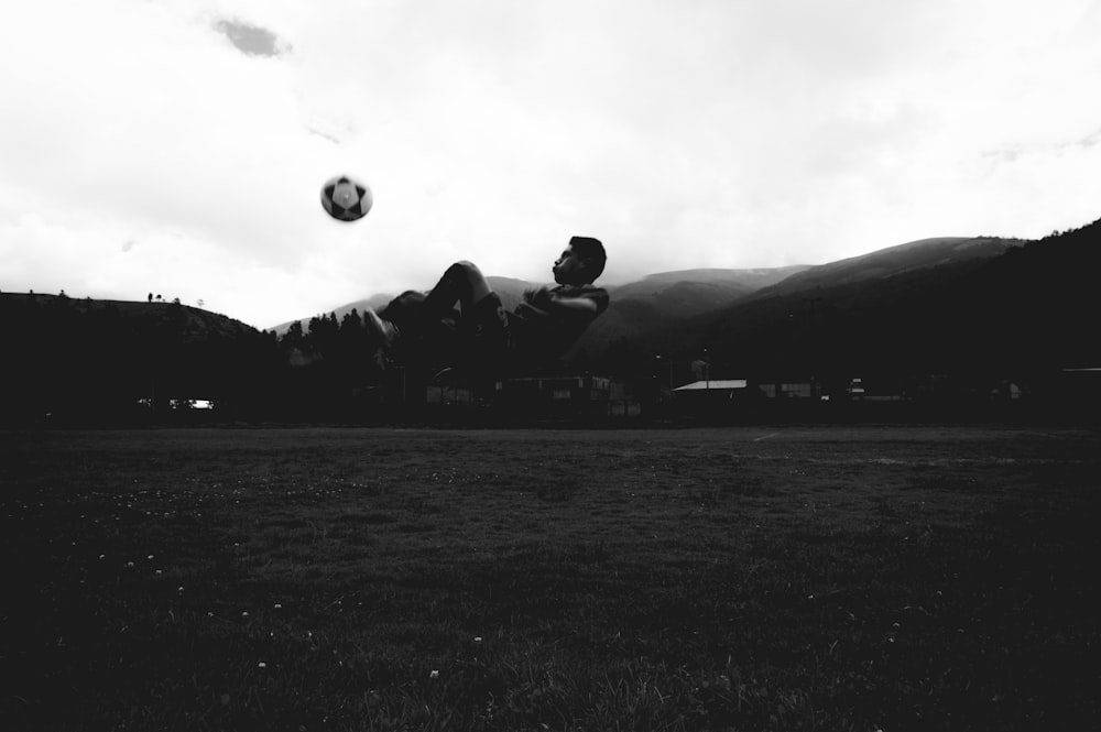 grayscale photo of man playing soccer