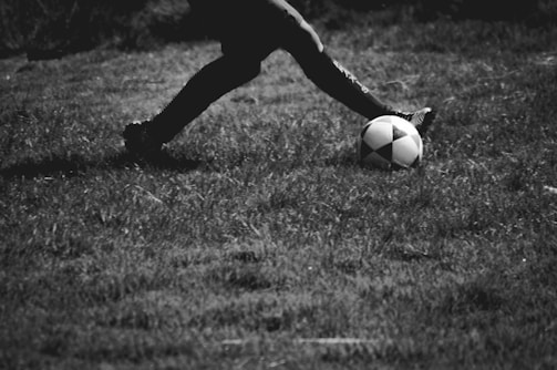 Photograph of a soccer player kicking the ball in an intense match.