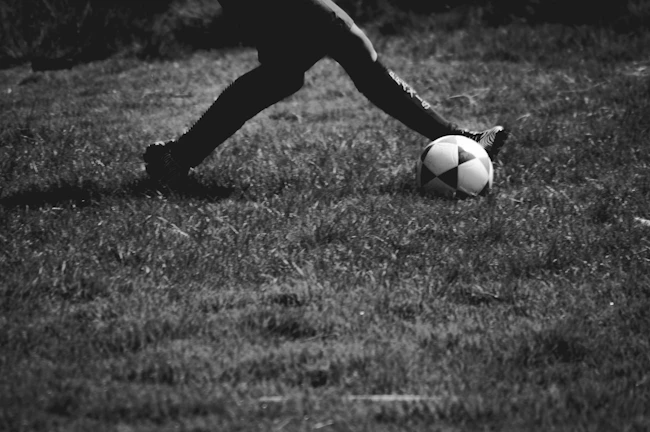 Action photo of Isabel kicking a football mid-air on a green pitch