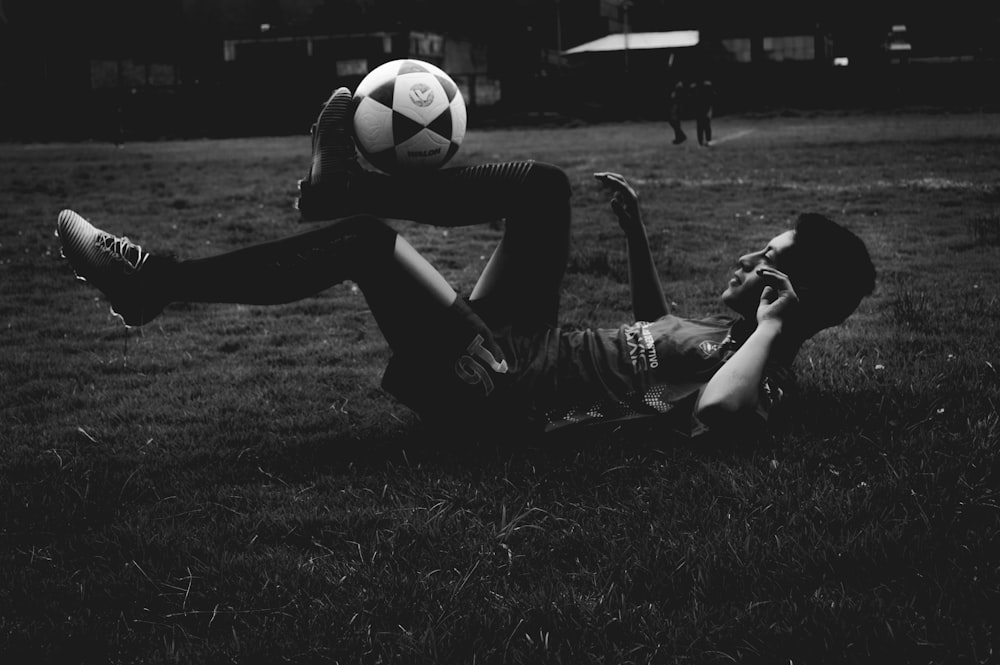 man lying on field while playing soccer ball