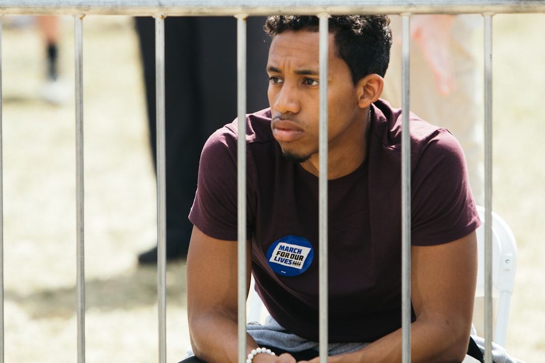  man sitting near metal fence rollong pin