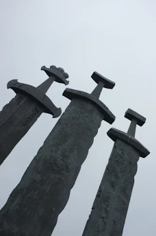 A detailed illustration of the Five of Swords tarot card showing a figure holding three swords with two defeated figures in the background under a cloudy sky.