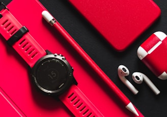 smartwatch, stylus, AirPods, and product red iPhone 7 on black surface