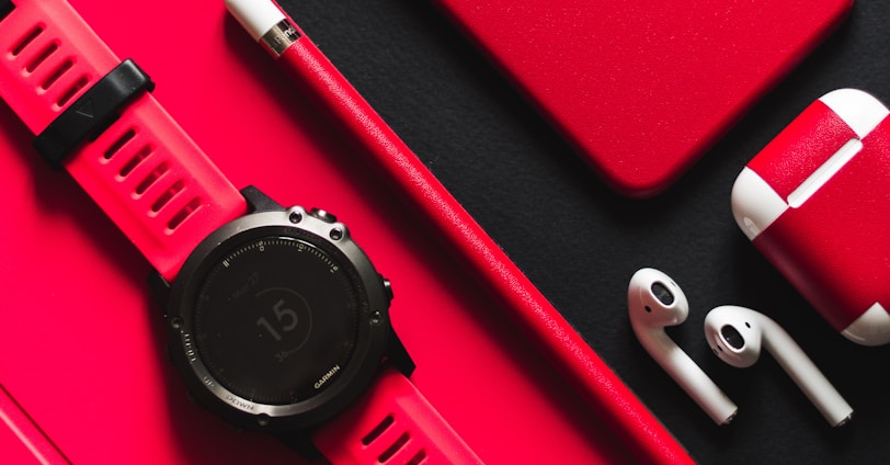 smartwatch, stylus, AirPods, and product red iPhone 7 on black surface