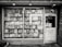 A black and white exterior view of an old bookstore featuring large display windows filled with an assortment of books. Signs on the window advertise ‘Old Books’ and ‘Literary History Walking Tour’. A variety of book titles are visible, and the shop door on the right displays more signage including a notice for a literary walking tour.