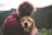 photo of man hugging tan dog