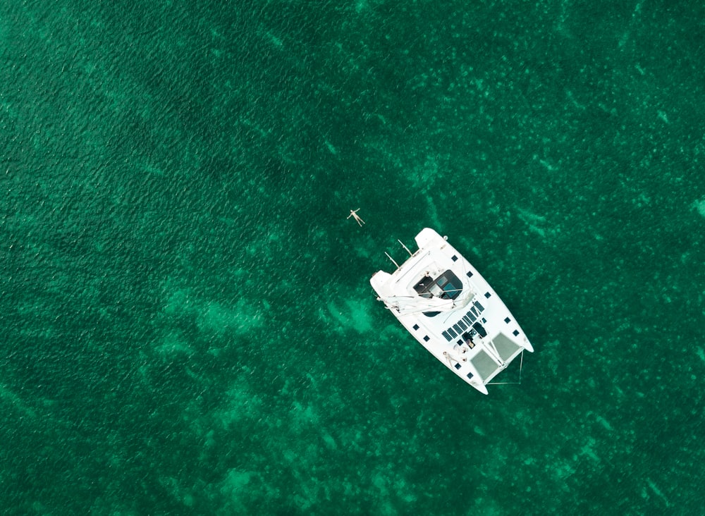 Photographie de vue aérienne d’un bateau blanc au milieu d’un plan d’eau pendant la journée