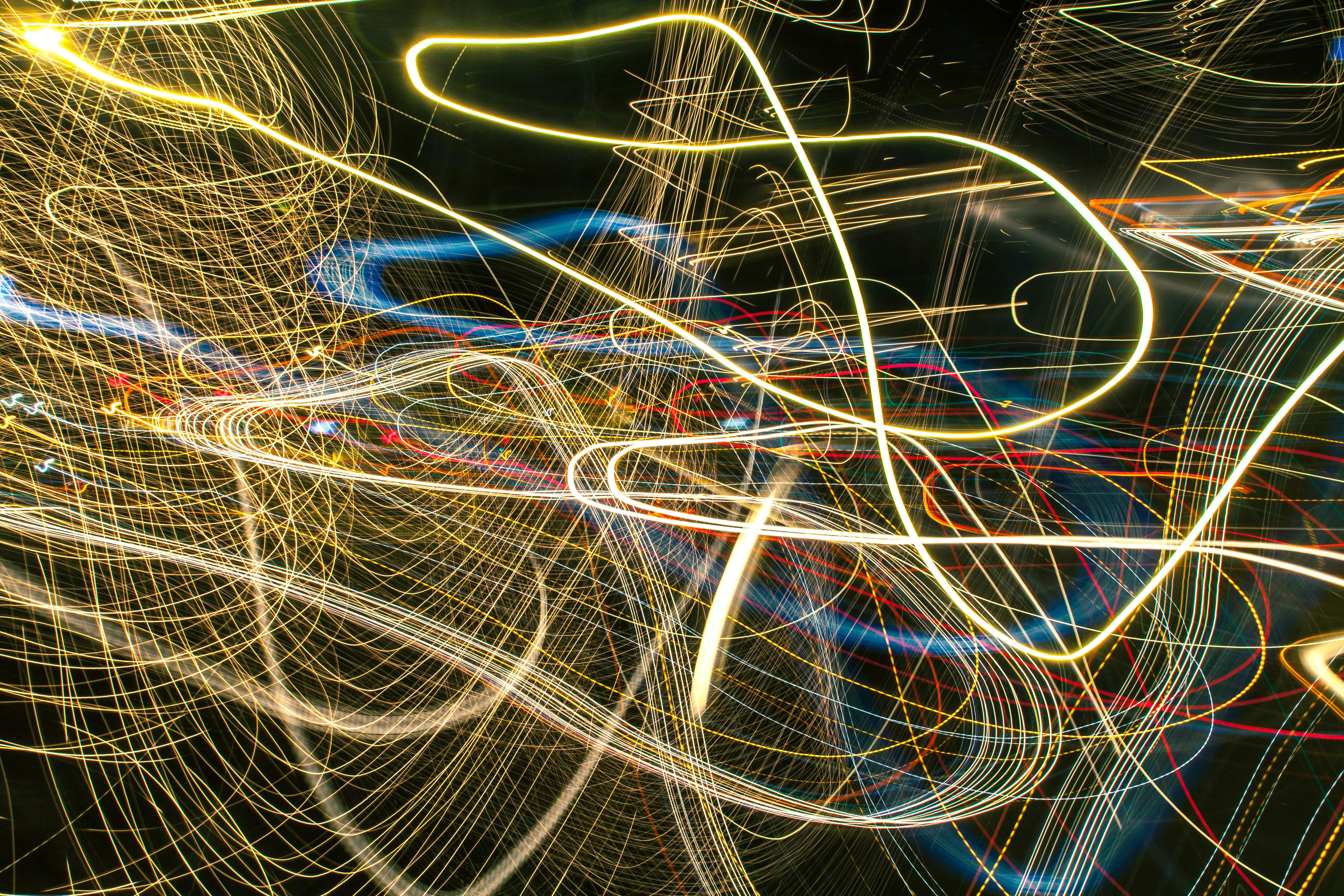 Abstract motion blur neon light trails on dark background, streaking orange and blue lines, cinematic dark atmosphere