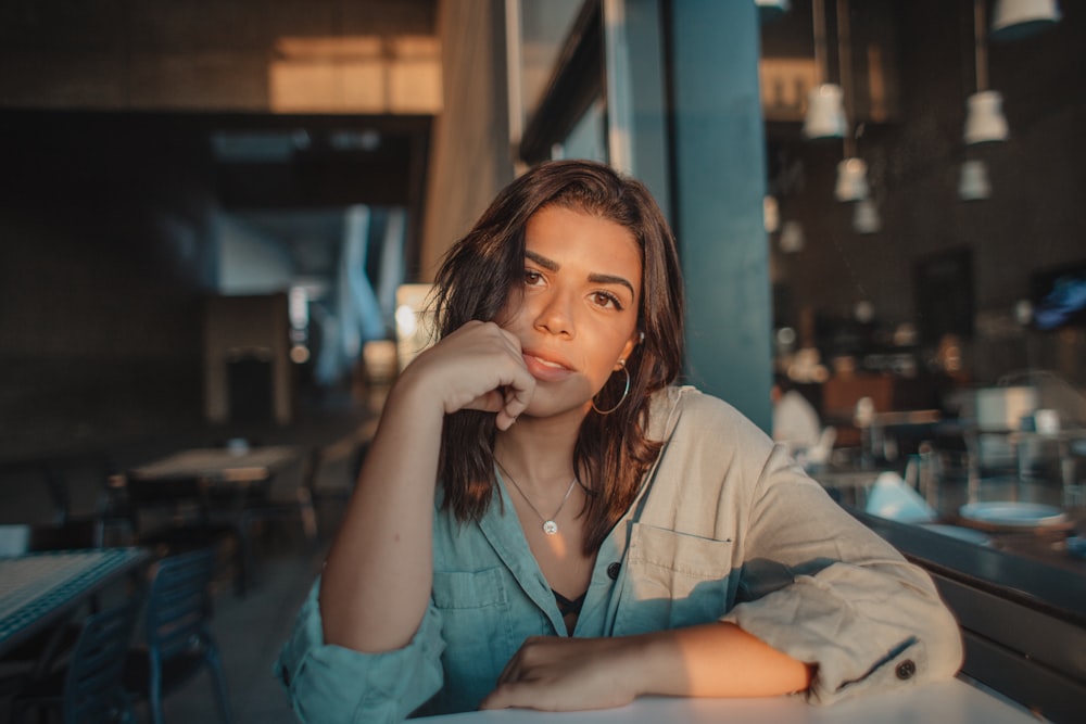 woman leaning on table near window