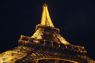 The Eiffel Tower illuminated at night, framed by Parisian street lamps.