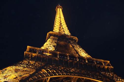 The Eiffel Tower illuminated at night, framed by Parisian street lamps.