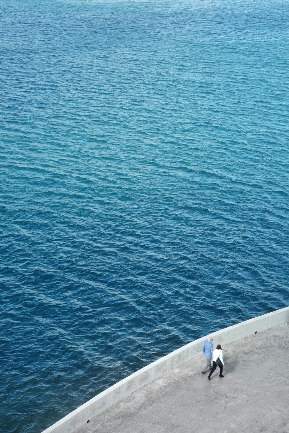 two persons walking near body of water