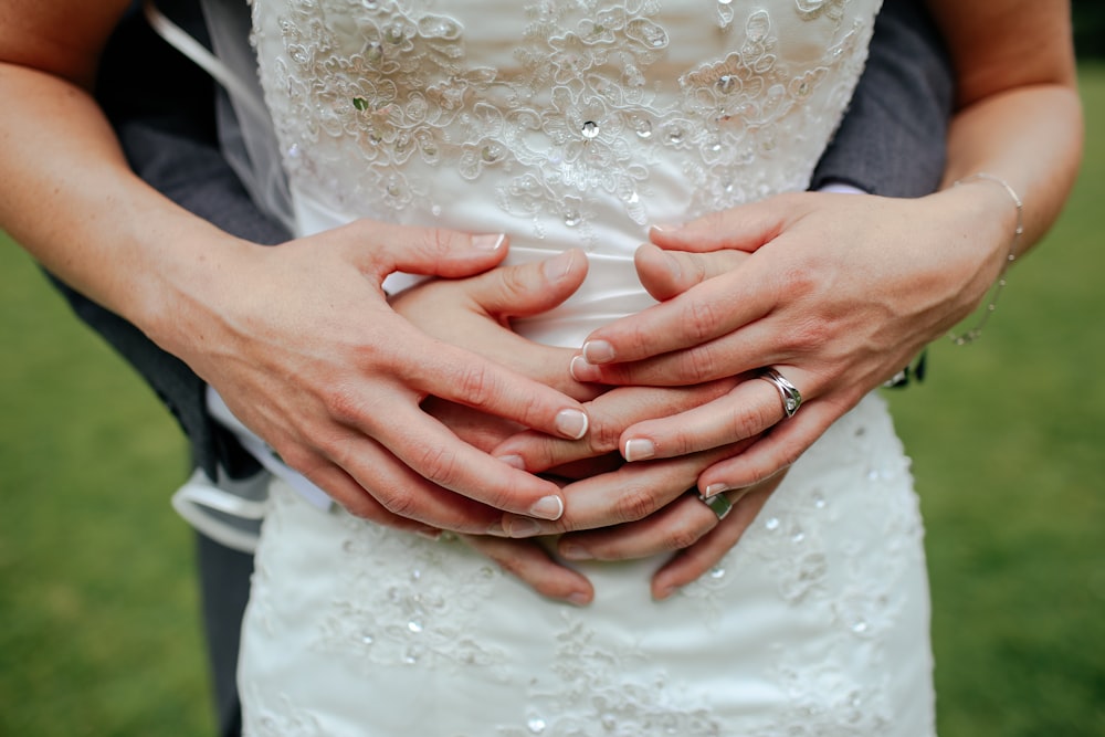 Fotografia de foco raso de pessoa abraçando uma pessoa em vestido branco