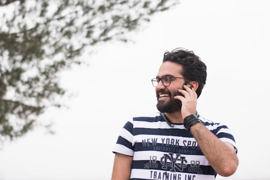 A friendly local business owner smiling while using a smartphone to chat with a web designer.