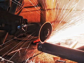 Industrial bandsaw cutting through thick metal with sparks flying in a workshop.