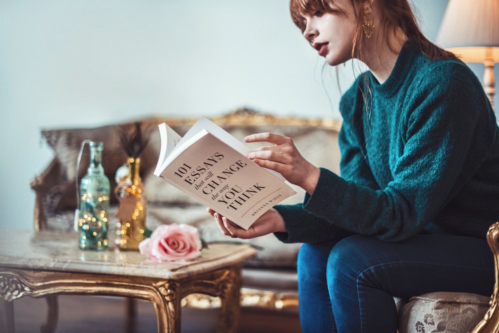 woman sitting down near table reading 101 Essays book