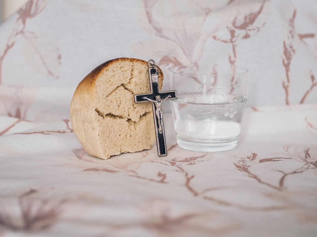 Crucifix pendant on bread beside glass